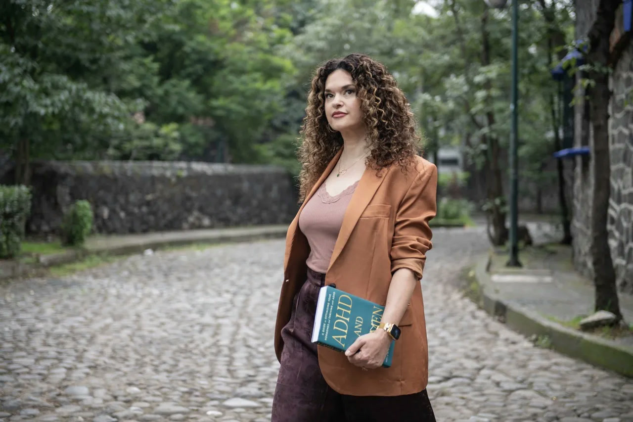 Dr. Brighten walking a cobblestone street carrying her book, ADHD and Women